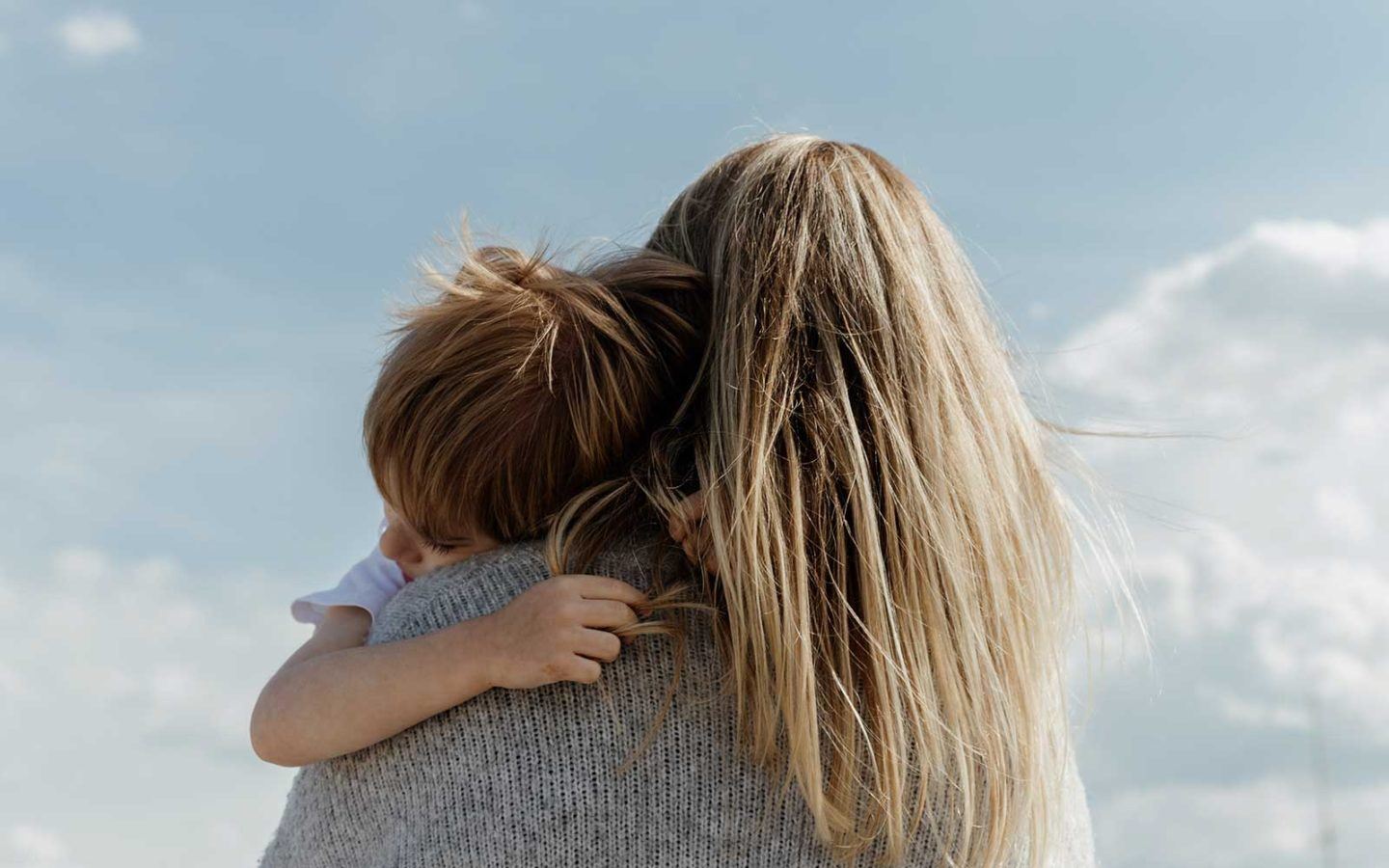 a behind view of a woman with blonde hair holding a young boy