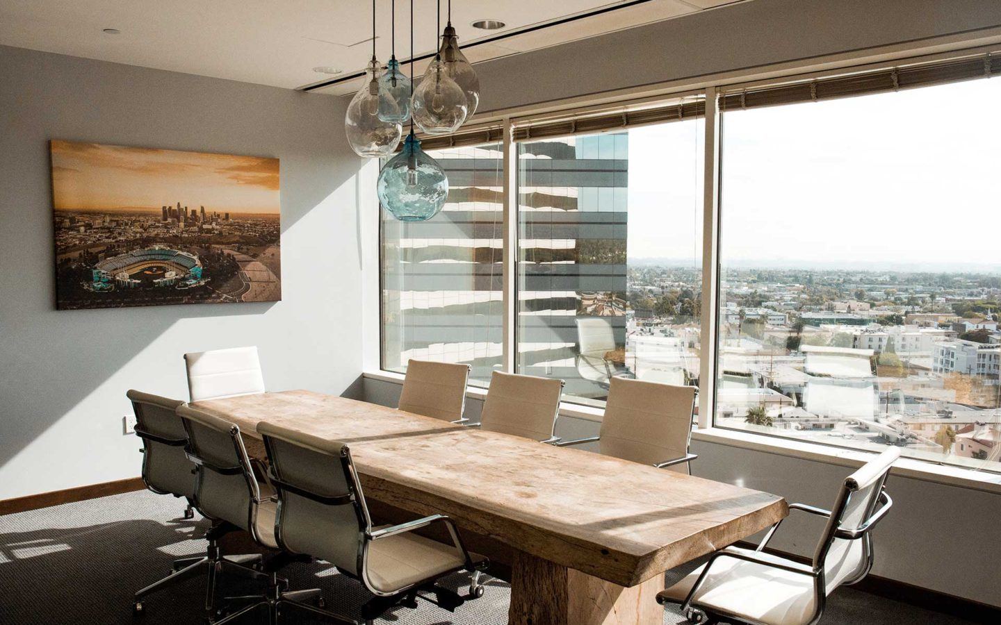 a wooden table surrounded by eight white office chairs