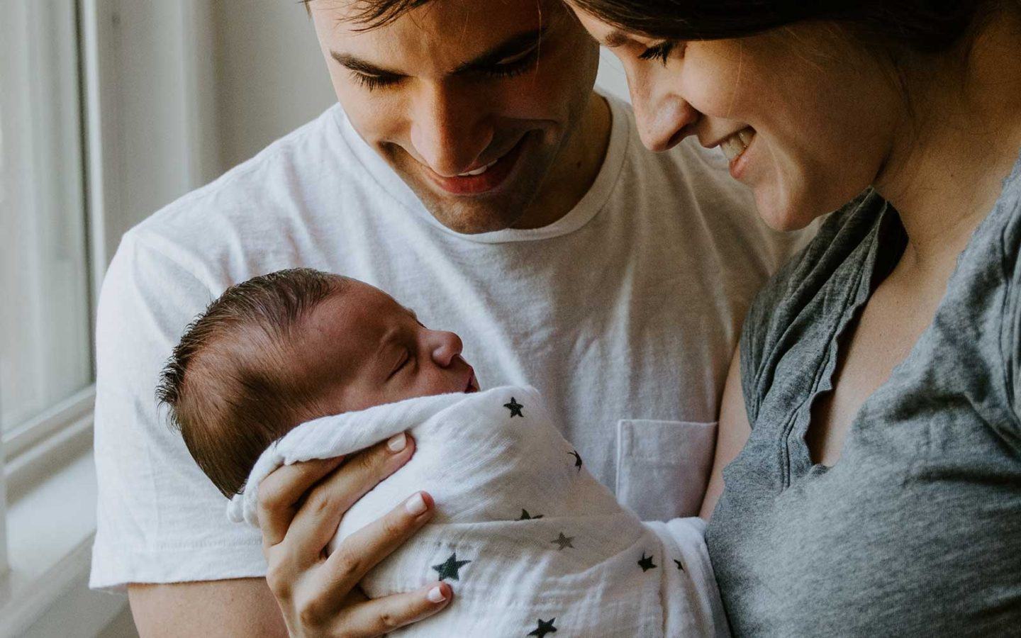 a man and woman holding a newborn baby smiling