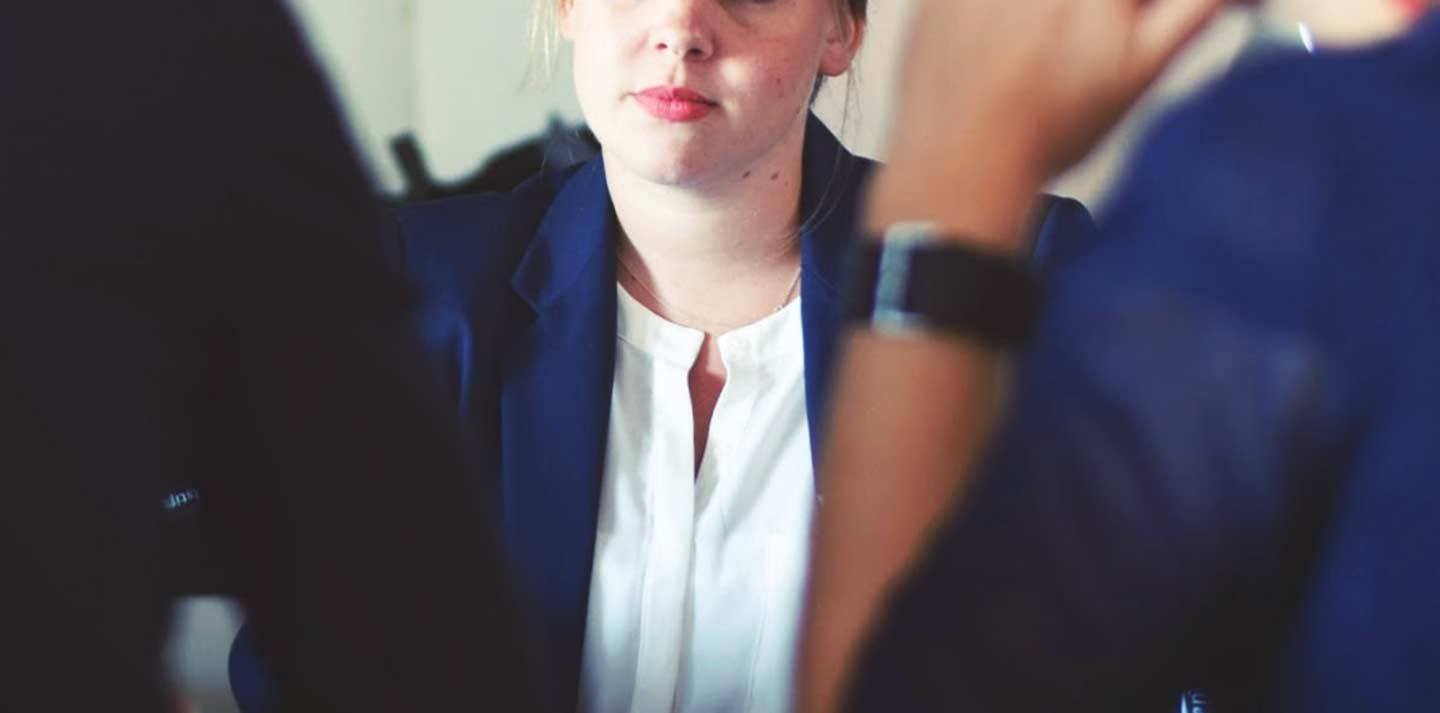a woman wearing a white shirt and a blazer in a meeting