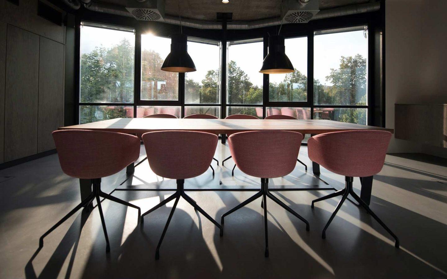 a meeting table with eight pink chairs in a loft style meeting room